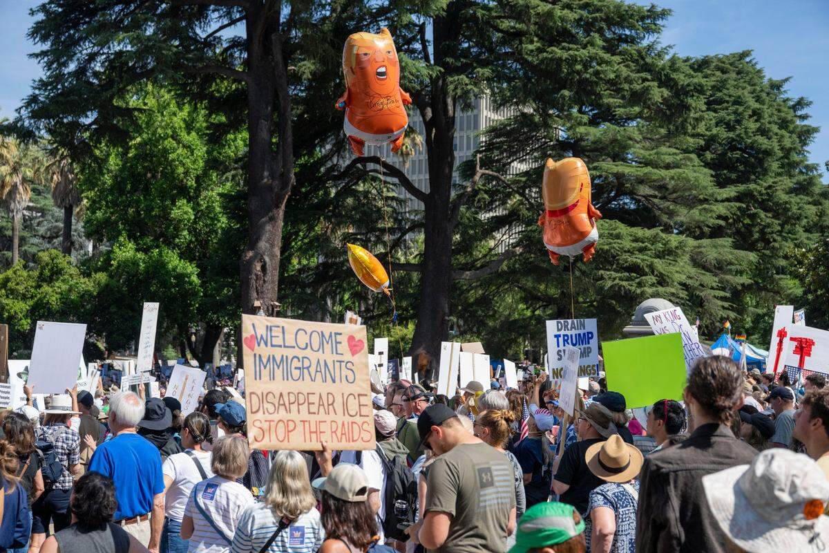 Balloons with the likeness of President Donald Trump fly over demonstrators at the Capitol during the “No Kings” protest against the Trump administration in downtown Sacramento on Saturday.