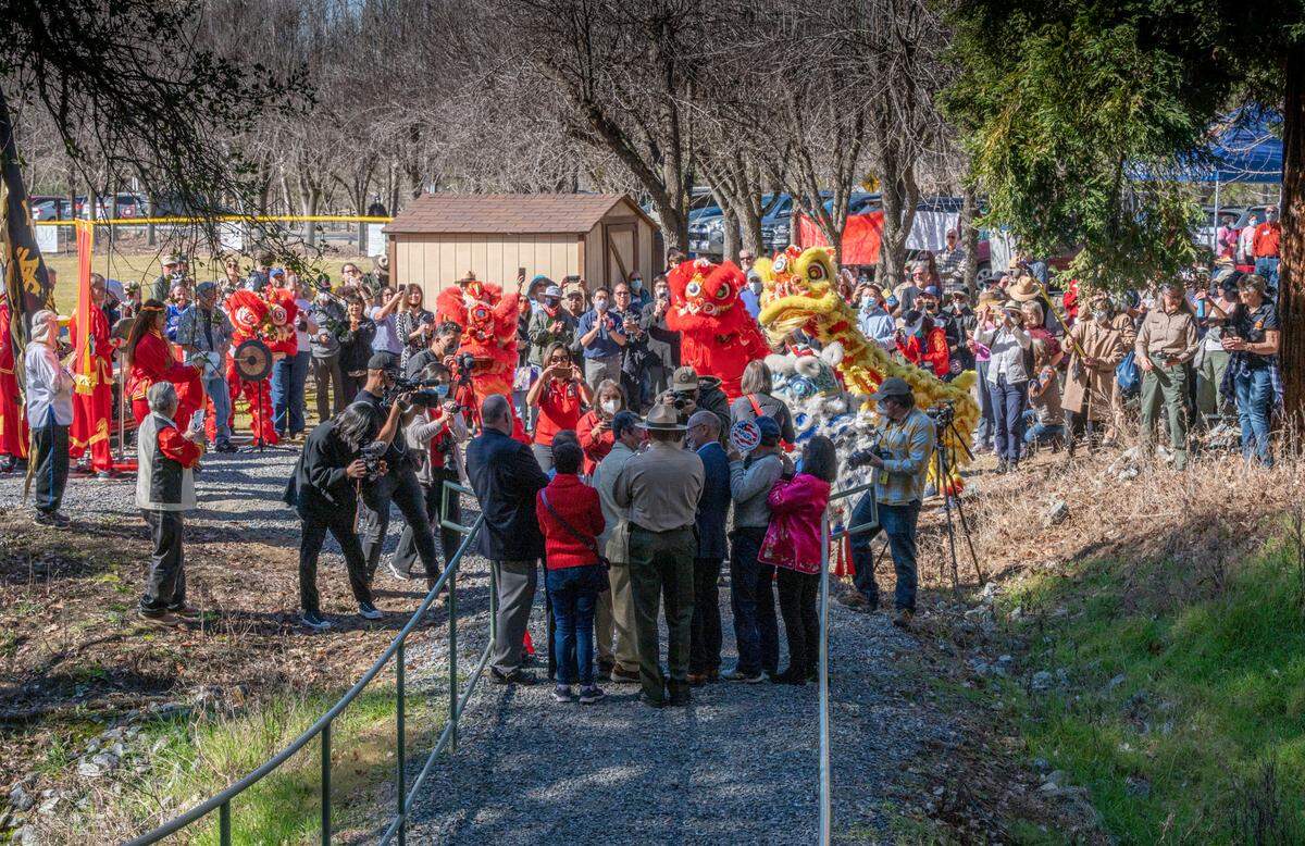 Participant in the dedication of the Gam Saan Trail, including a few lion dancers, celebrate the ribbon cutting on Friday, Feb. 11, 2022 in Lotus.