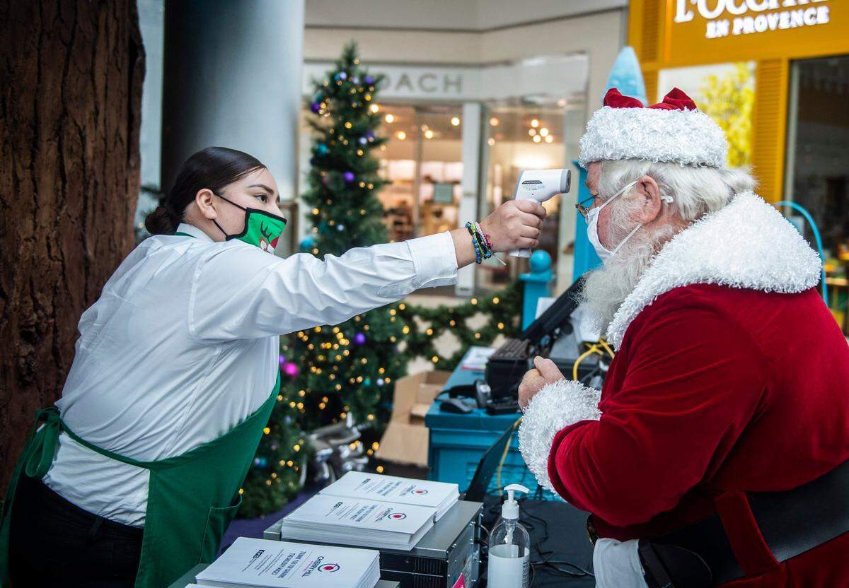 Sales associate Chantal Gomez checks Arden Fair mall Santa Claus Richard Harreld before he starts his shift on Sunday, Dec. 6, 2020. The mall’s annual Santa photo opportunity is contactless this year, and masks are required, because of the coronavirus.