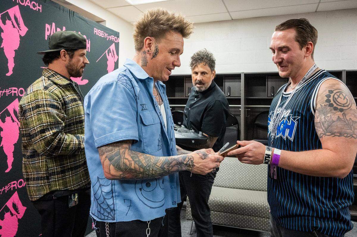 Jacoby Shaddix, lead singer of Papa Roach, meets with fan Anthony Amorin of San Jose while drummer Tony Palermo, right, and and bassist Tobin Esperance sign a guitar before their show at Golden 1 Center on Saturday, March 28, 2025.