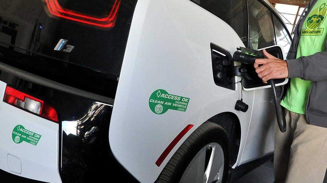 A BMW electric vehicle with two green Clean Air Vehicle Decals visible on its rear bumper is connected to a charging station in Huron in 2018. The stickers, which allow solo drivers of electric vehicles to use California’s carpool lanes, will become invalid after Sept. 30 as a federal law enabling the program expires.