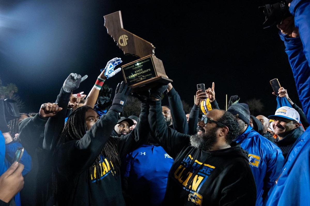 Grant Pacers coaches hold the state trophy in the air in celebration after their team won the 2022 CIF State Football Division III-AA Championship on Saturday, Dec. 10, 2022, at Grant High School in Sacramento. The Pacers won 36-34.