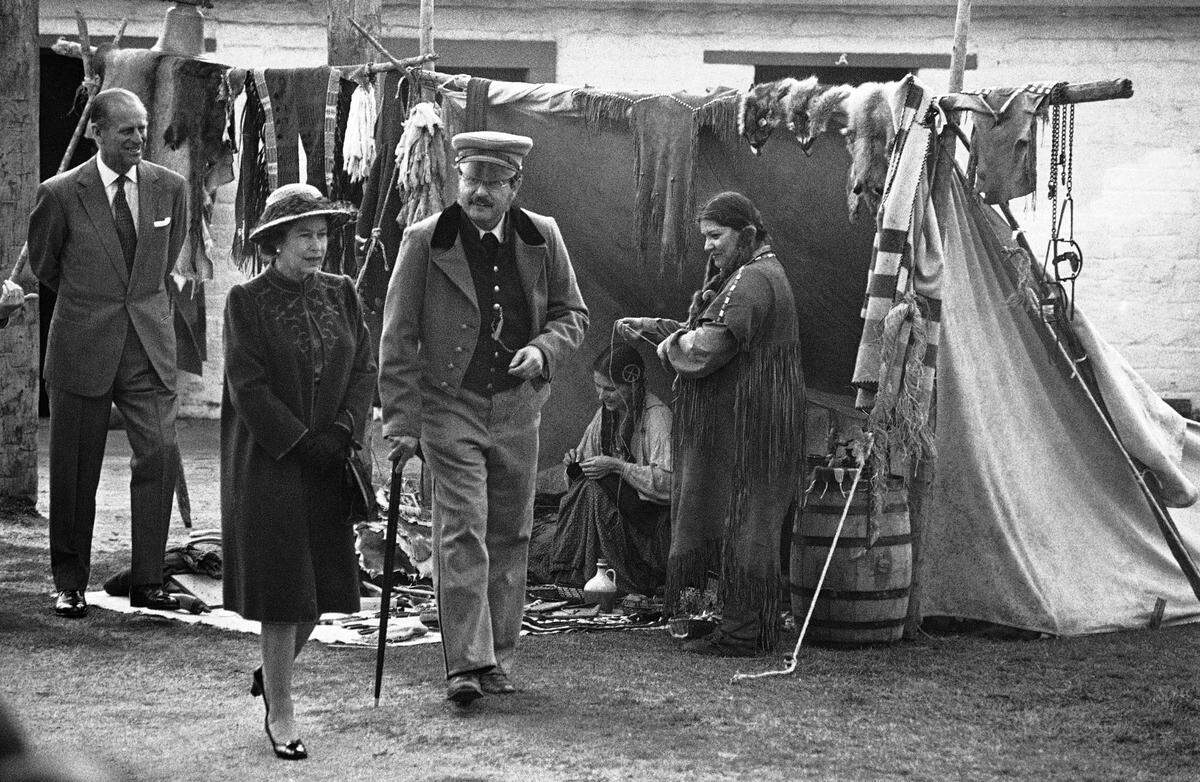 Queen Elizabeth II, trailed by Prince Philip, walks past historical reenactors on Friday, March 4, 1983 during her tour of Sutter’s Fort.
