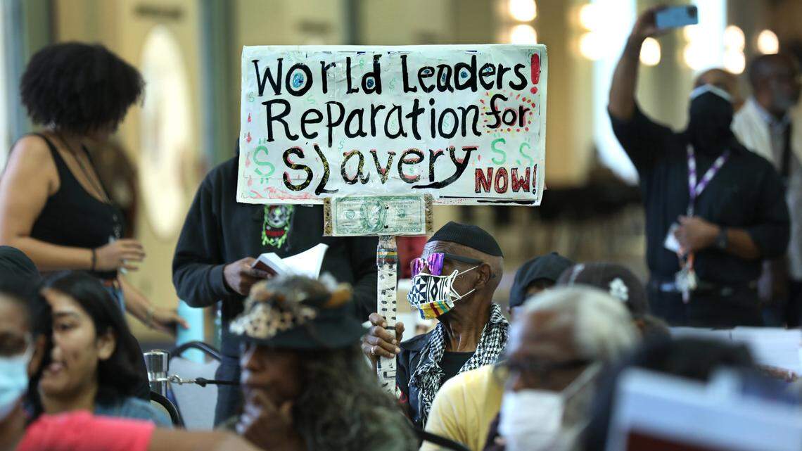 Walter Foster, 80, of Los Angeles, raises a sign calling for a focus on financial compensation as the California Reparations Task Force takes public comment in Los Angeles in September.