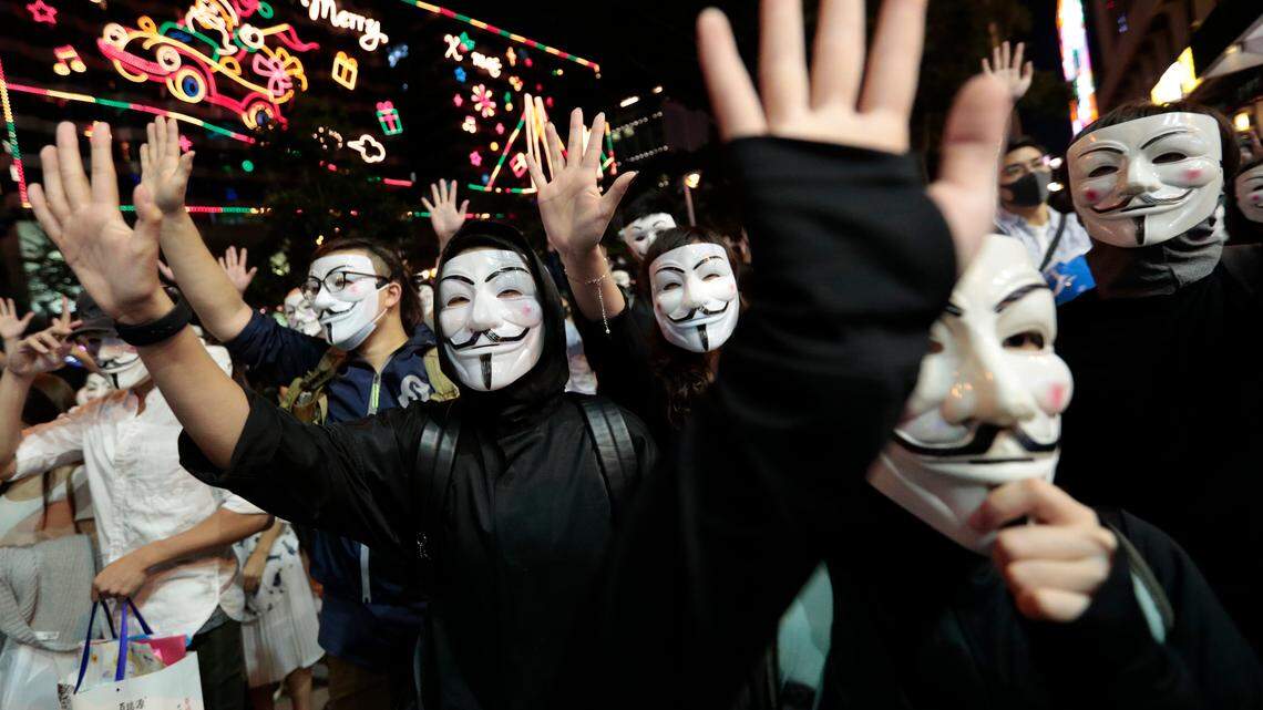 Protesters in Guy Fawkes masks raise their hands as they chant slogans during a rally in Hong Kong on Nov. 5. In California, protesters in robes and Guy Fawkes masks blocked off entrances to Westminster Woods in Sonoma County, on Friday.