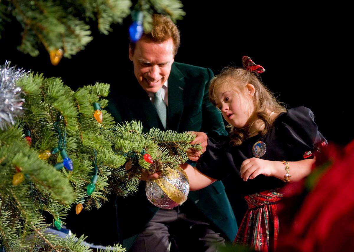 Gov. Arnold Schwarzenegger joins eight-year-old Michaela Tritch of Los Angeles on stage as she places the last ornament on the tree and before lighting the state Capitol Christmas tree in 2008.