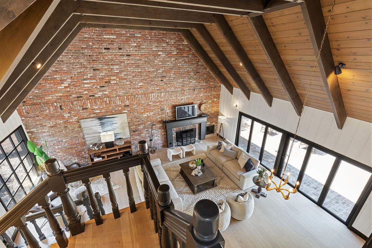 Heritage meets contemporary style inside, where soaring ceilings, exposed beams, and walls of windows fill the home with natural light and luxury — every detail honoring Buzz Oates’ original Tudor vision.
