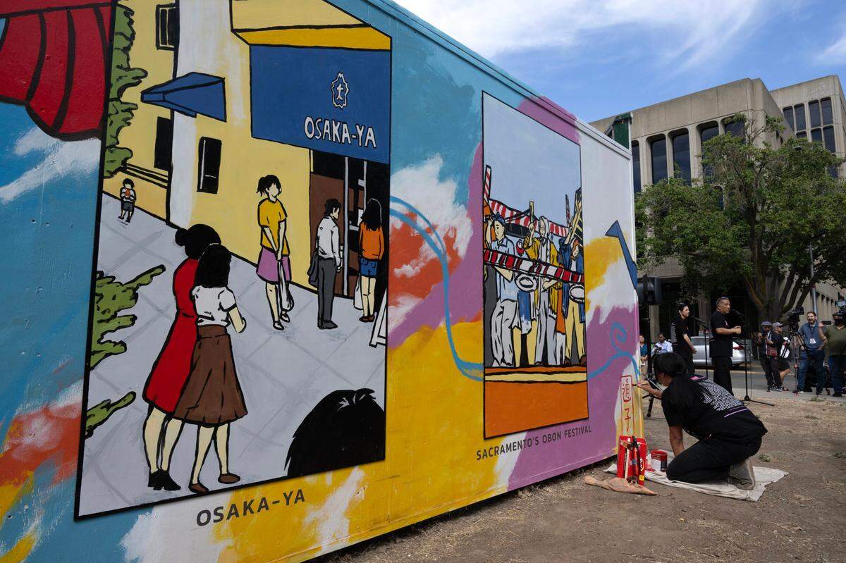 Artist Karen Tsugawa makes a rakkan-in, an artist’s signature, on the Sacramento Japantown mural located at Capitol Mall and 4th Street on Wednesday.