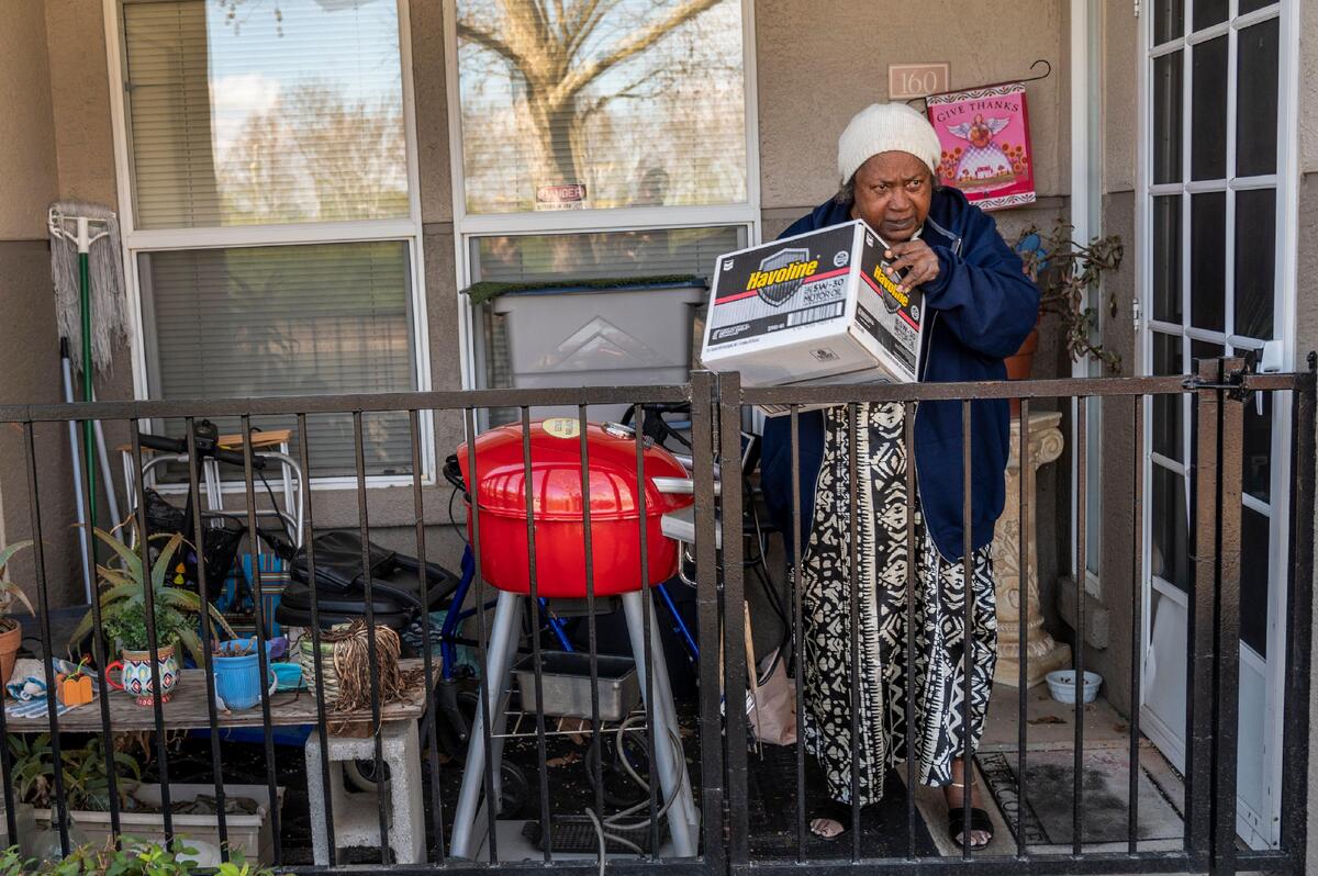 Peggy Belcher, 79, lifts a box of freshly delivered groceries in Elk Grove on Tuesday, March 24, 2020. The volunteers call them on the phone to alert them they are outside with the box. They then ring the doorbell and step back to allow the seniors to come out and get the boxes.