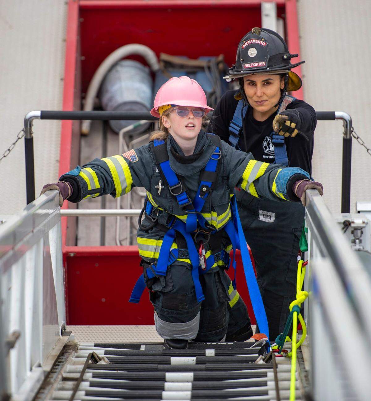 Reese Blankenship, 10, looks up the aerial ladder before she climbs as Hailey Machado, of the Sacramento Fire Department, points to the tower at the Sacramento Area Girls Fire Camp at McClellan Park in Sacramento on Saturday, Oct. 23, 2021. Blankenships father, Adam Blankenship, a member of Sacramento Fire Department, volunteered at the camp.