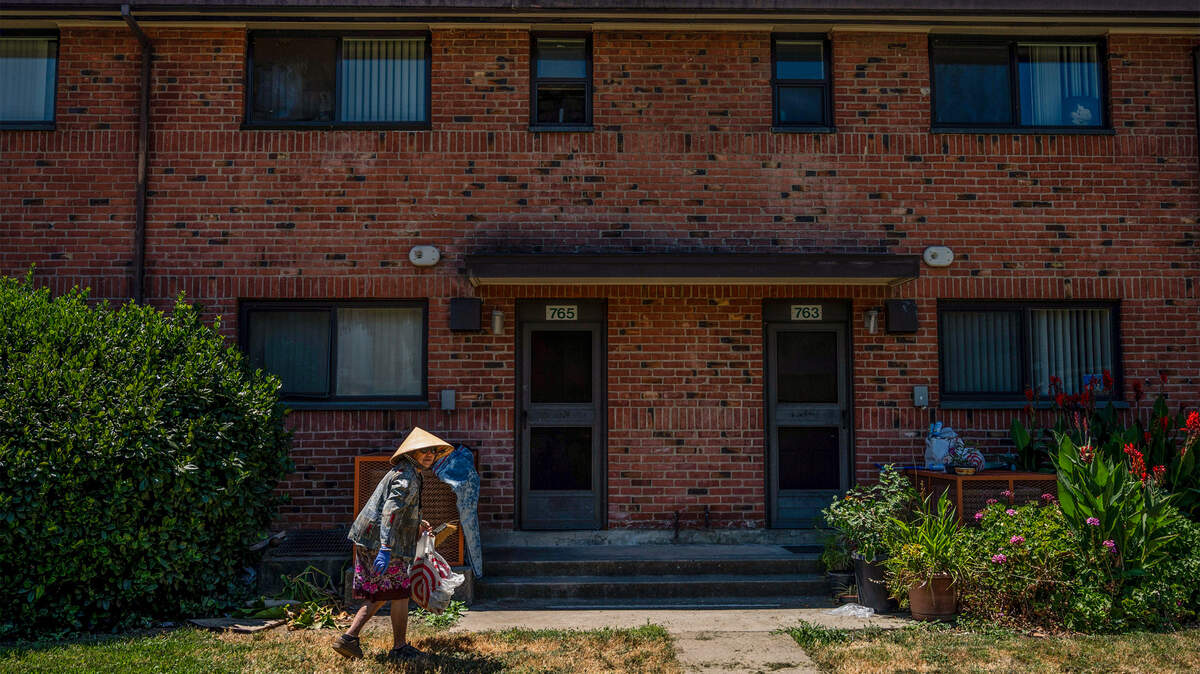 A woman cleans the grassy area in front of an apartment at the Alder Grove housing complex in 2020. Security has been stepped up in the Upper Land Park public housing development after back-to-back shootings this month.