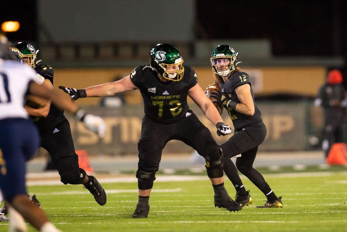 Sacramento State Hornets quarterback Jake Dunniway (12) looks downfield to pass, as offensive lineman Jackson Slater (72) blocks, against Northern Arizona University during the first half of the Hornets’ homecoming NCAA football game Saturday, Oct. 23, 2021, at Hornet Stadium in Sacramento.