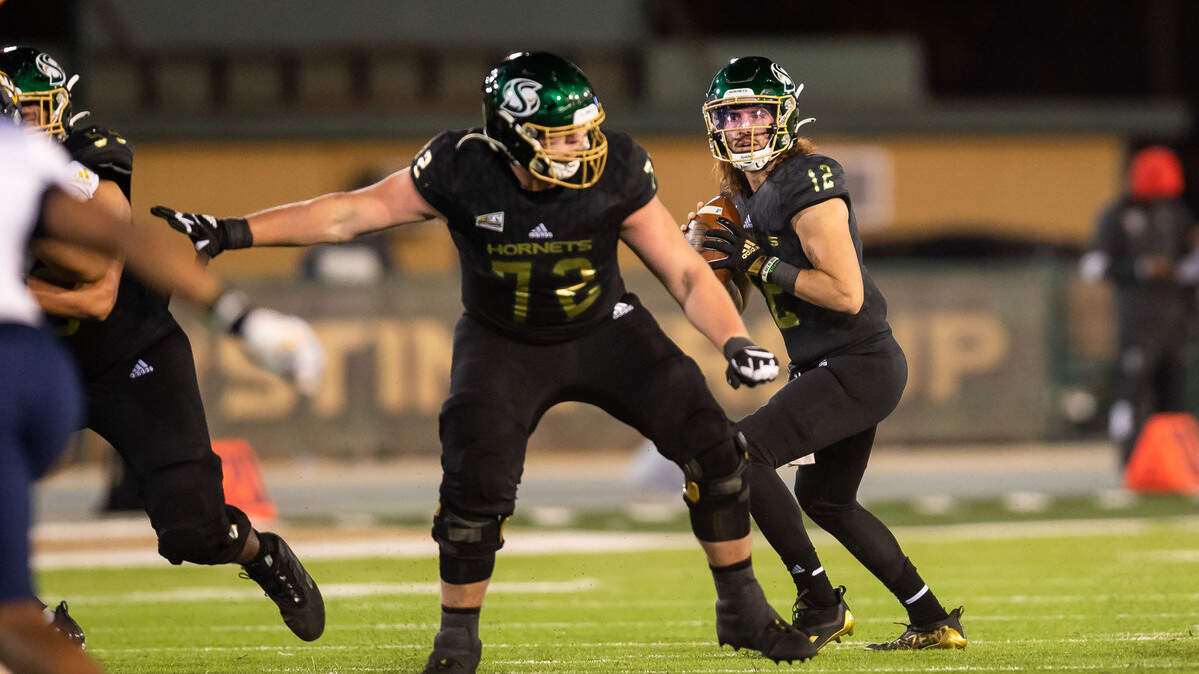 Sacramento State Hornets quarterback Jake Dunniway (12) looks downfield to pass, as offensive lineman Jackson Slater (72) blocks, against Northern Arizona University during the first half of the Hornets’ homecoming NCAA football game Saturday, Oct. 23, 2021, at Hornet Stadium in Sacramento.