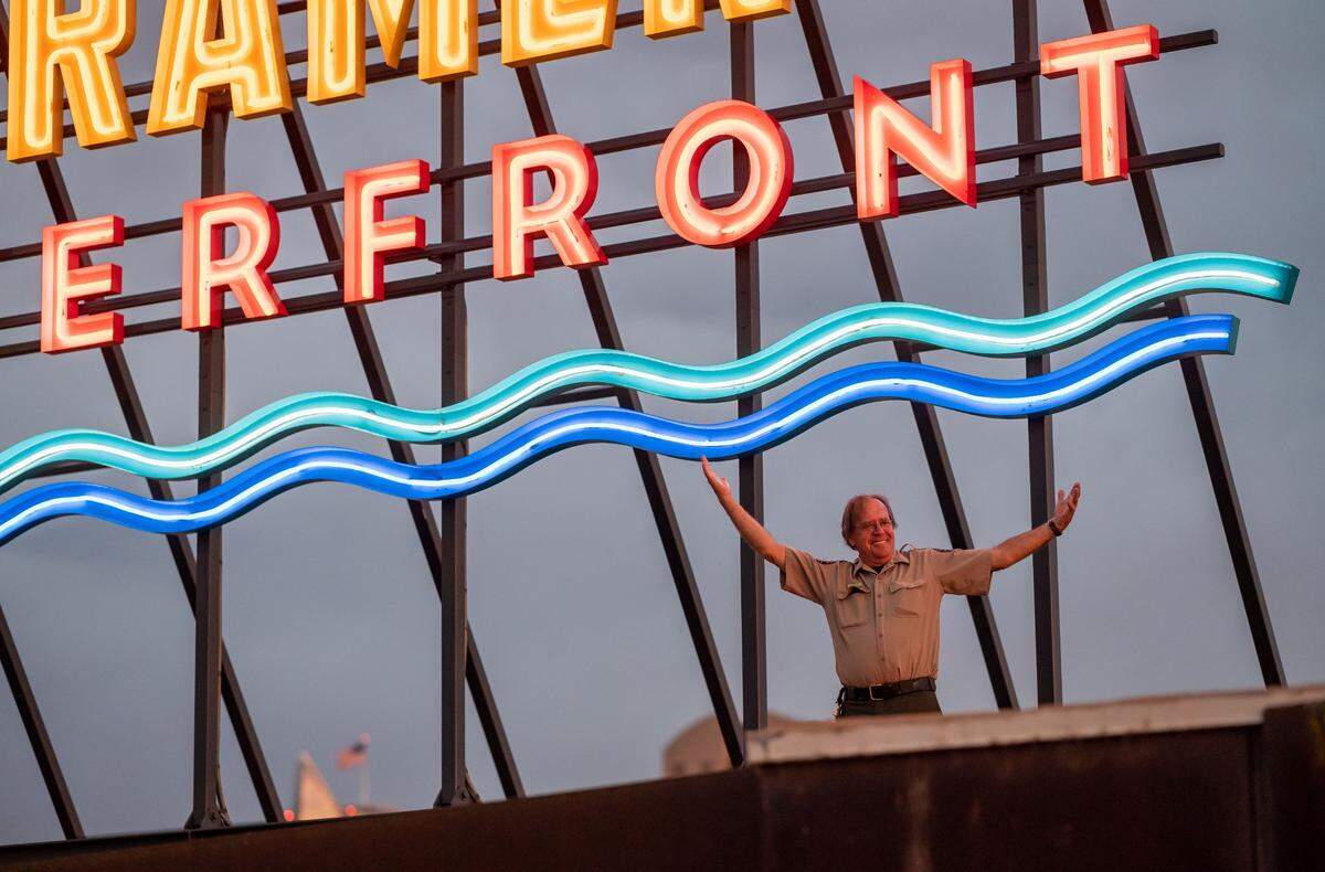 California State Parks Maintenance Supervisor Mike Newby, who helped facilitate the first lighting of the neon-alternative LED Old Sacramento Waterfront sign, poses for colleagues under the new landmark atop the California State Railroad Museum on Wednesday, June 22, 2022, in Old Sacramento.