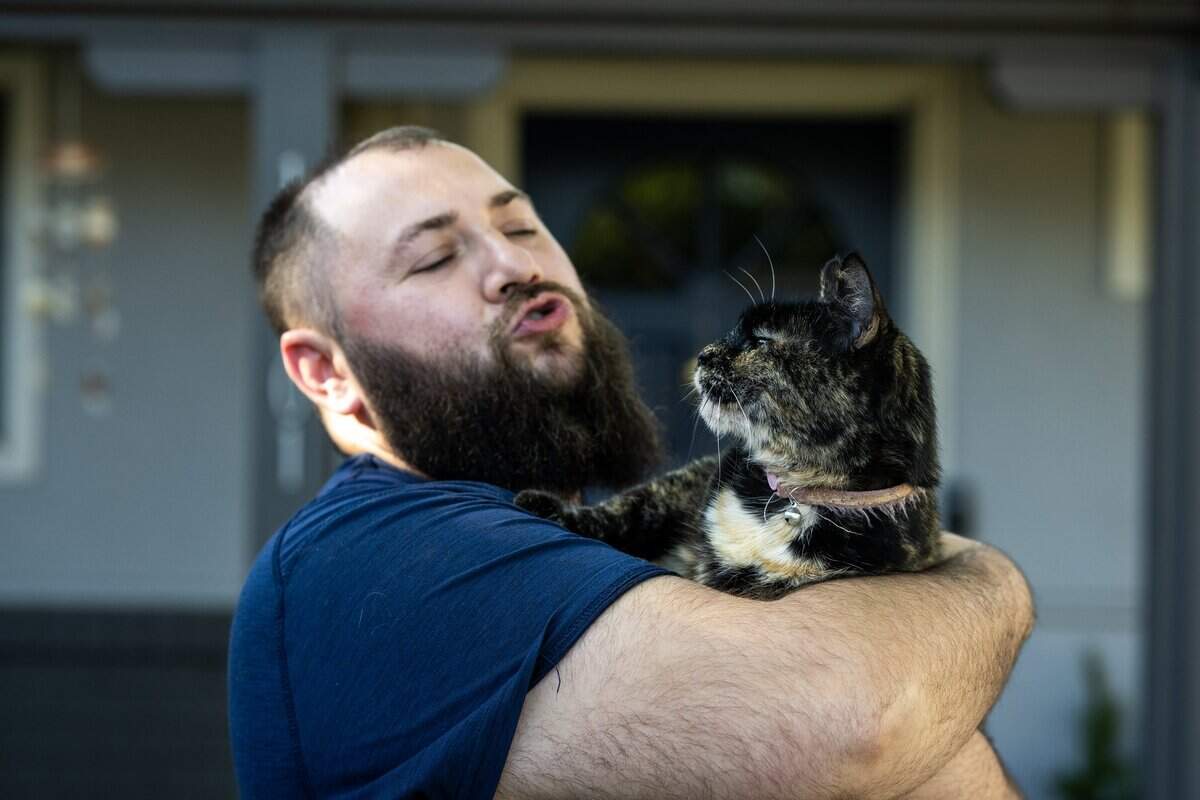 Chris Commander embraces his cat Xena on Wednesday in Rancho Cordova. Xena was sprayed by a postal worker outside their home Monday.