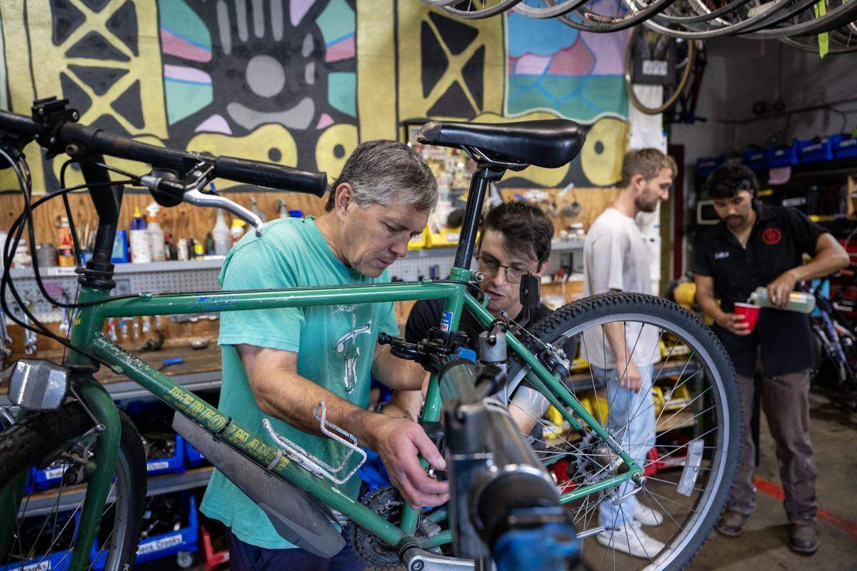 Joey Shemuel gives Mark Stivers guidance on repairing the chain on his bike at the Sacramento Bicycle Kitchen on Tuesday, May 5, 2026.
