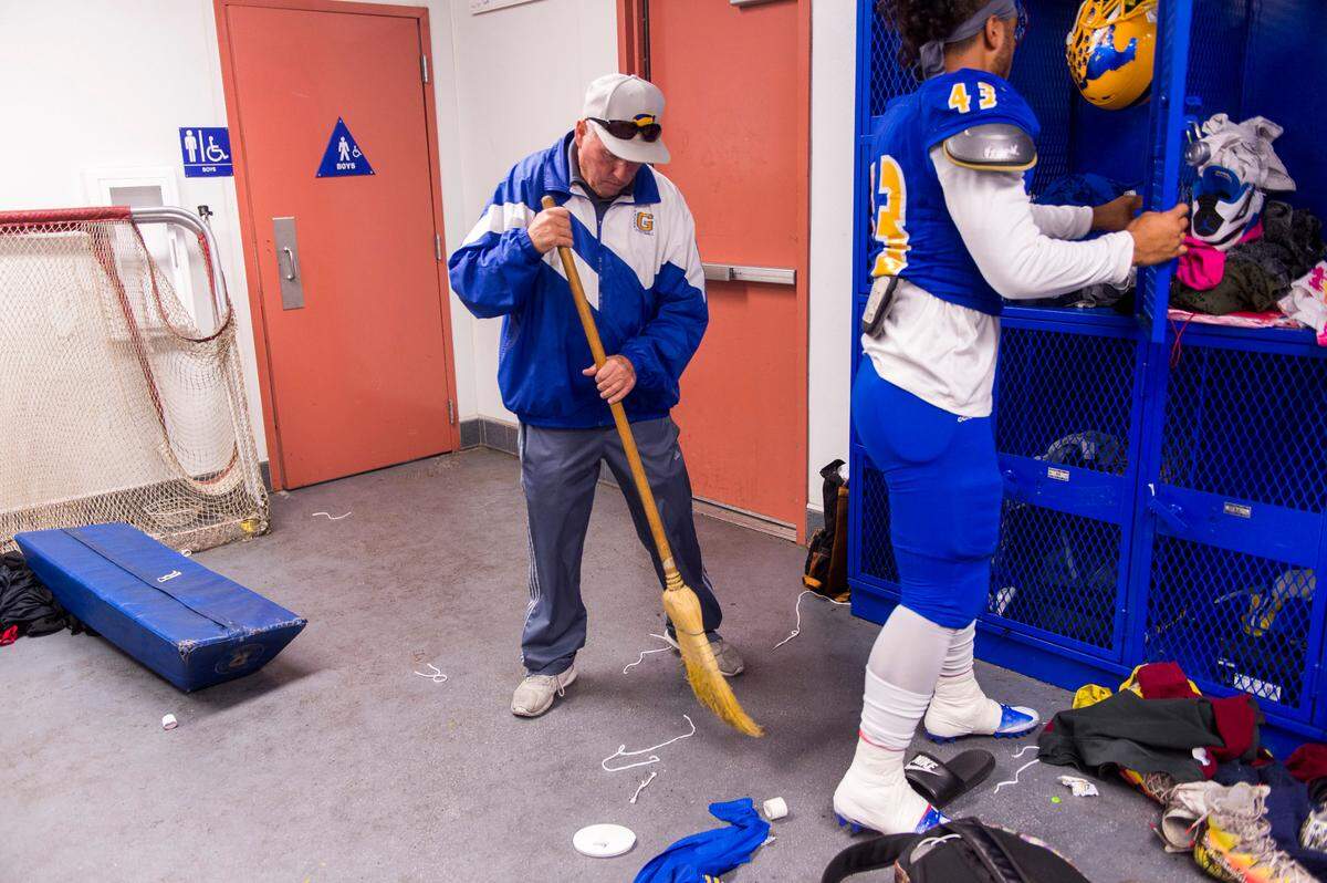 Grant Pacers head coach Mike Alberghini sweeps up trash in the locker room before a game against Sheldon on Oct. 20, 2017.
