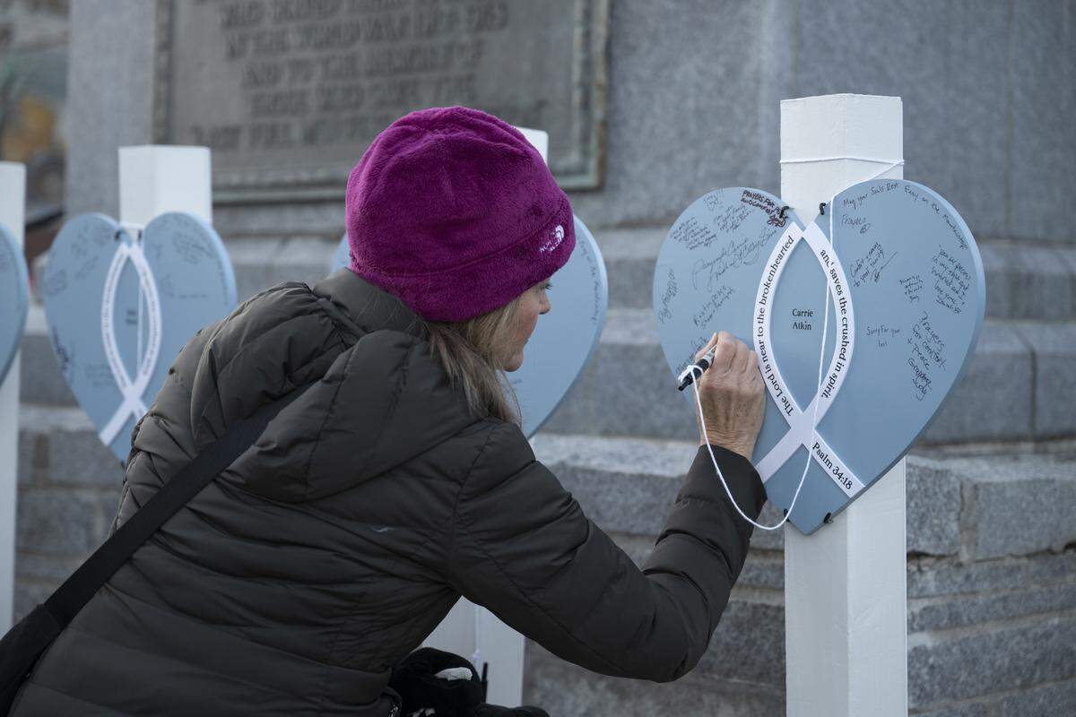 Karin Shepamek writes a message on a heart during a vigil in downtown Truckee on Sunday, in honor of the victims of a deadly avalanche that struck the Lake Tahoe area the previous week.