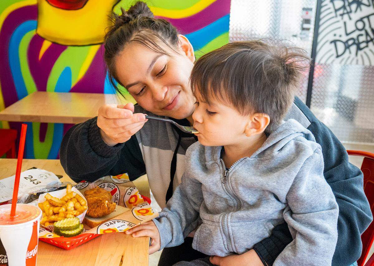 Alexis Hernandez, left, feeds Tristen Ufland Jr., right, macaroni and cheese during the opening of Dave’s Hot Chicken in Fair Oaks on Wednesday.