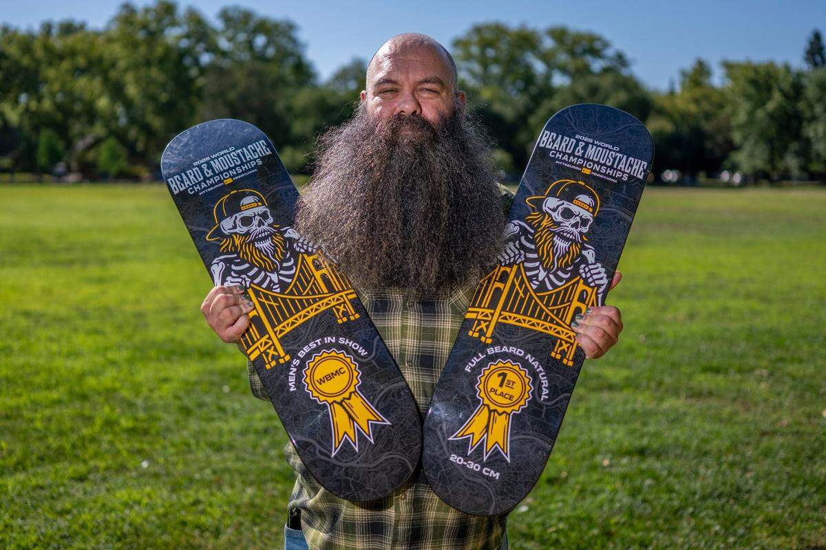 Trevor Mustafa, the 2025 Beard and Moustache world champion, holds his awards in West Sacramento on Thursday. Mustafa won first place in his category of beards 20-30 centimeter in length, as well as overall best in show.