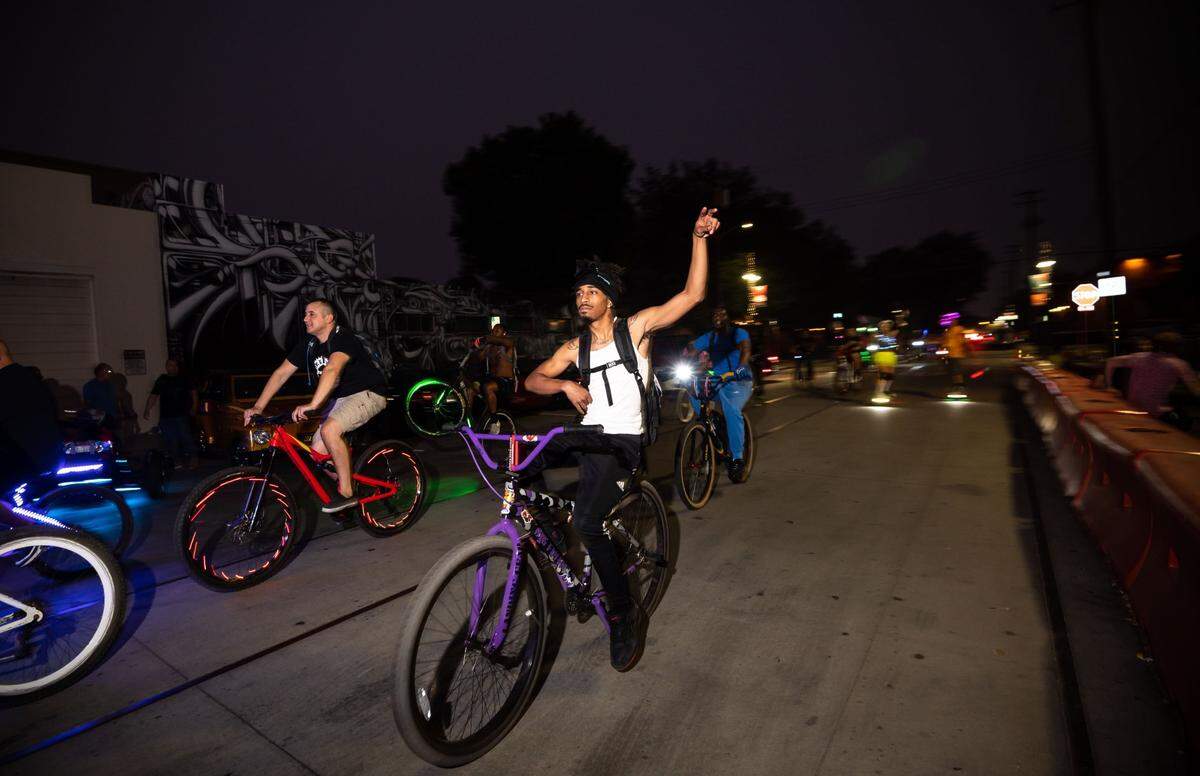 Riders on bicycles with colored lights and other audio and visual effects ride west on R Street, as outside-diners and onlookers take in the sight, through midtown as they participate in the monthly Bike Party Sacramento ride Friday, Aug. 6, 2021, in Sacramento.
