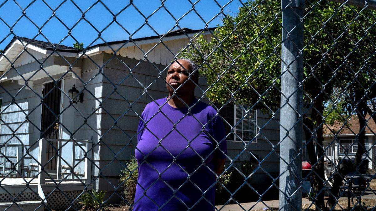 Lenora Jackson stands near a broken fence outside a house she rents in South Oak Park in 2022. She said that when she came home from her job as a state worker in April, her property manager was standing outside her house trying to evict her because of a bedbug infestation.