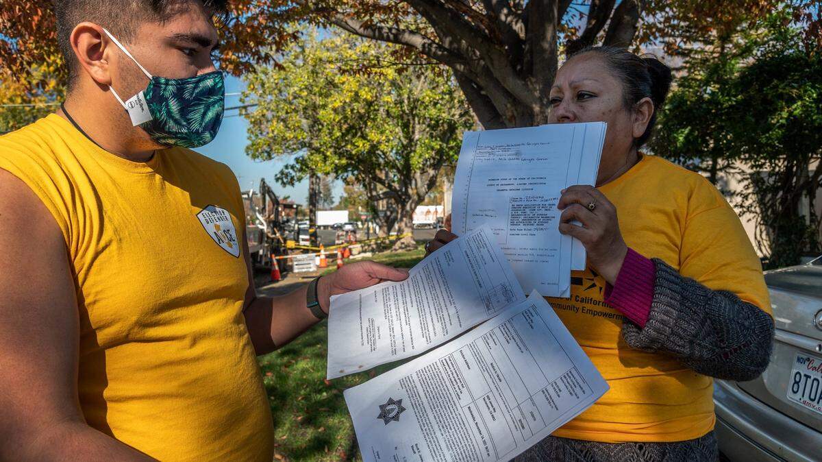 Luis Fernando Anguiano, Communications Associate for Alliance of Californians for Community Empowerment (ACCE) holds eviction and legal papers alongside Eduviges Garcia, right, who is on the verge of eviction with her two daughters and three grandchildren outside their rental home on Monday, Nov. 22, 2021.