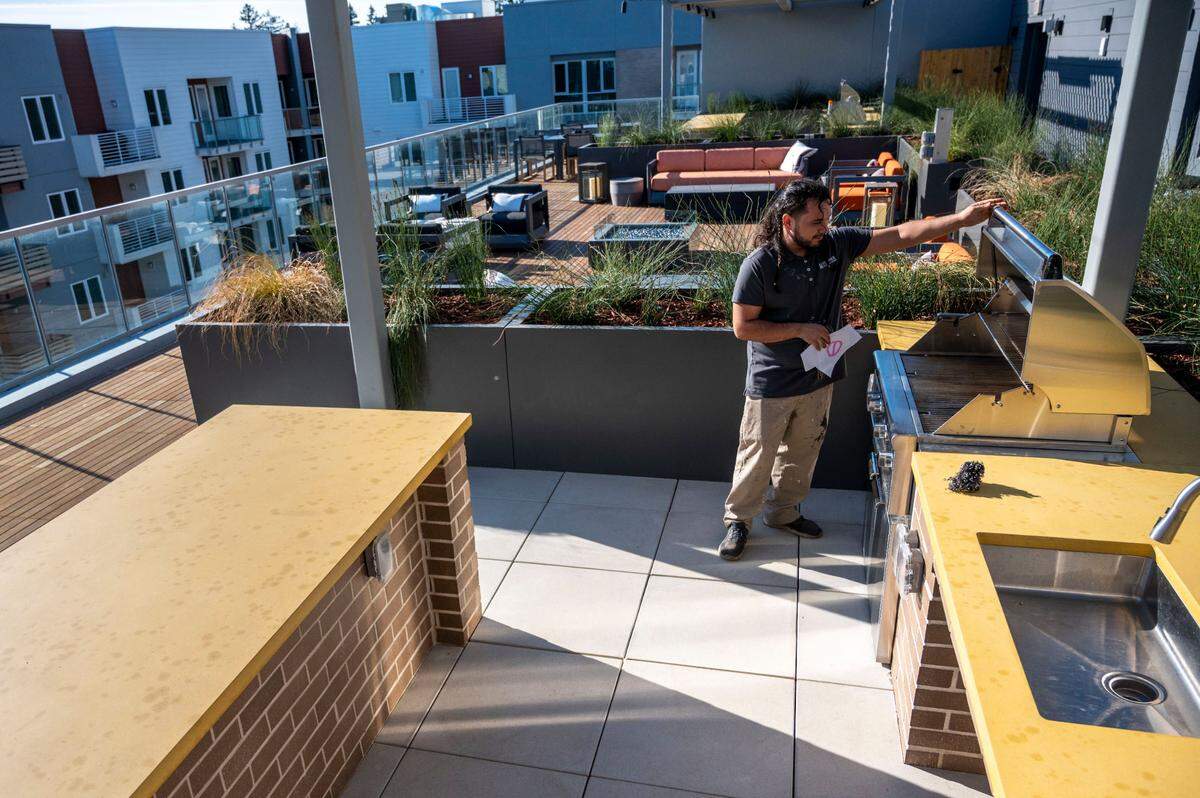 A worker with Weidner Apartment Homes checks a barbeque grill on the rooftop area at Capitol Towers apartment complex in downtown Sacramento earlier this month.