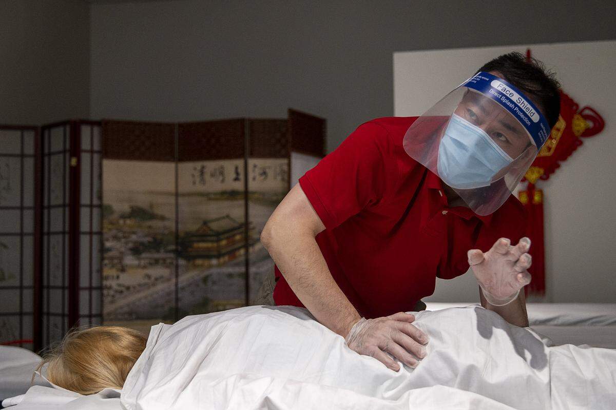 Zhen Wan of YW Massage wears gloves, a face mask and a clear plastic face shield as he massages a customer at the Yuba Sutter Mall on Wednesday, May 6, 2020 in Yuba City. It was the first day the mall was open after county health officials allowed retail stores to reopen in defiance of the state’s stay-at-home order to slow the spread of the coronavirus.