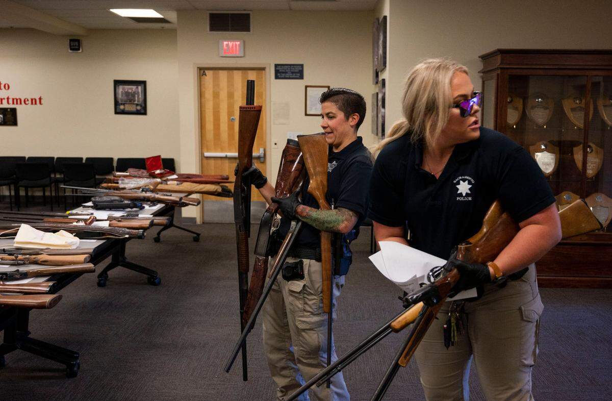 Officers Katie Rappazzo, left, and Lindsey Smith look for a spot to place a big donation of firearms brought in by a participant at the Sacramento Police Department’s gun buyback event on Saturday at the police headquarters. Officers collected 275 firearms at the event.