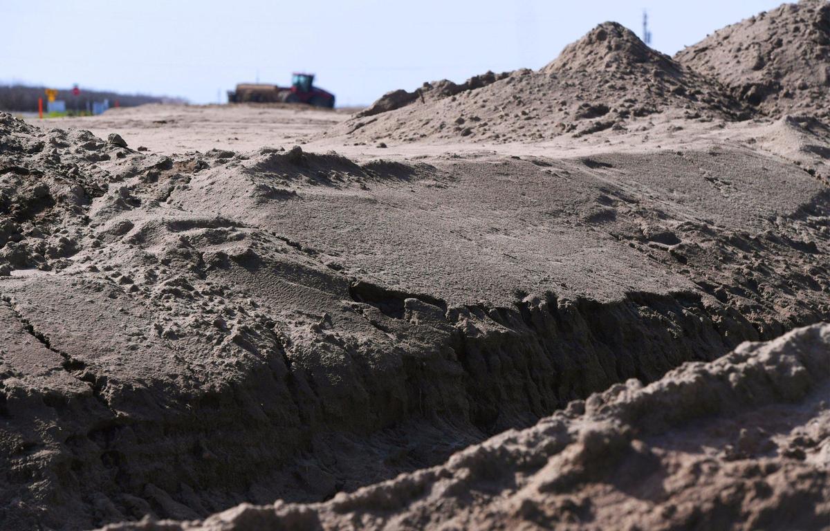 Sandy soil, compacted from recent rain, creates an embankment around a 20-acre basin with heavy machinery seen in the distance. The basin is hoped will recharge the local aquifer. Photographed Friday, March 3, 2023 near Madera.