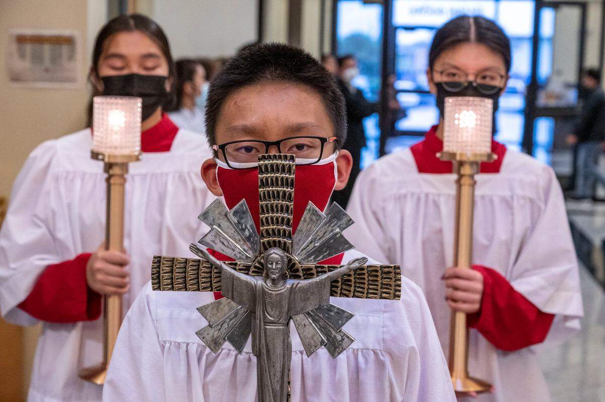 Young members of the Vietnamese Martyrs Parish in south Sacramento carry a cross and candles as they walk down the aisle to celebrate Holy Thursday.