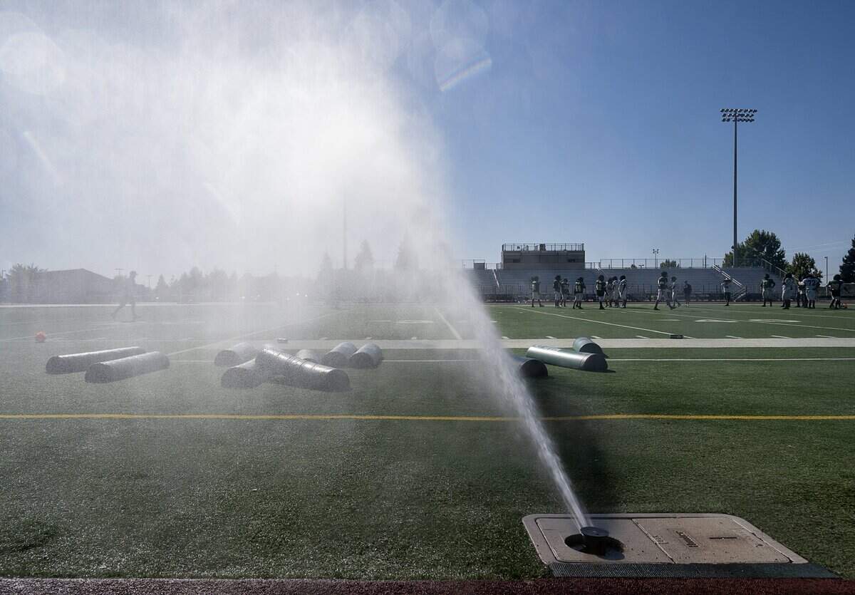 Monterey Trail High School football players practice under water sprinklers on campus in Elk Grove on Aug. 13, 2019.
