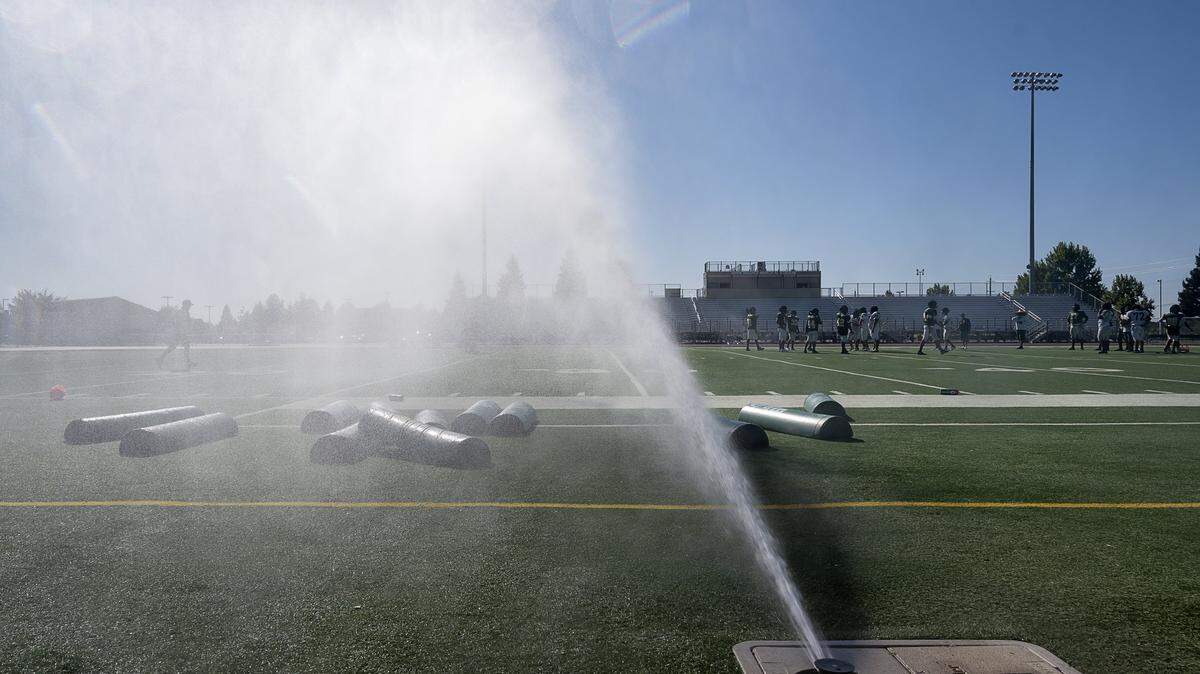 Monterey Trail High School football players practice under water sprinklers on campus in Elk Grove in 2019.