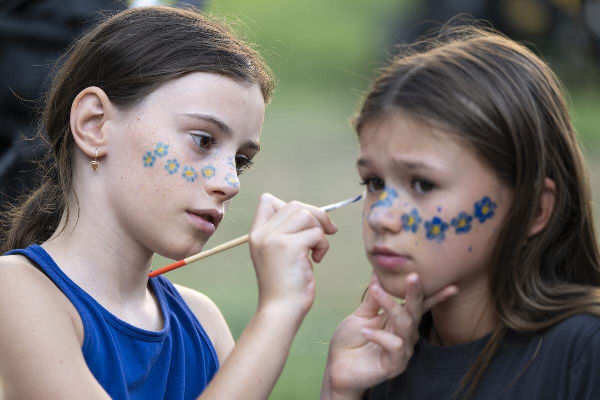 Alina Boiko, left, paints flowers in Ukraine’s colors on Marianna Bryk’s face during a Ukrainian Independence Day celebration at the California Capitol in Sacramento on Sunday.
