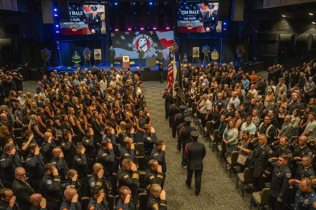 Hundreds stand and salute as a procession enters a memorial for Fire Engineer Tim Hall at Creekside Church in Elk Grove on Tuesday.
