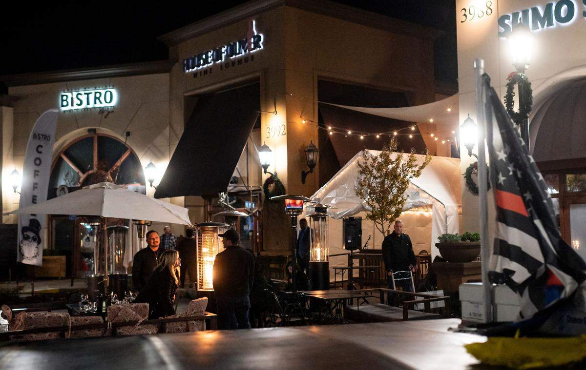 Employees close up as patrons stand outside and a musician packs up at House of Oliver Wine Lounge on the first night of a 10 p.m. to 5 a.m. curfew Saturday, Nov. 21, 2020, in Roseville. Gov. Gavin Newsom announced the overnight stay-at-home order, restricting non-essential activities, for most of California in an effort to slow the spread of the coronavirus.