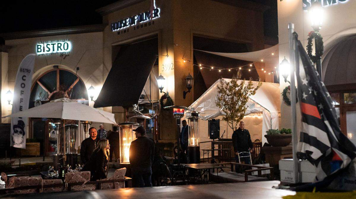 Employees close up as patrons stand outside and a musician packs up at House of Oliver Wine Lounge on the first night of a 10 p.m. to 5 a.m. curfew Saturday, Nov. 21, 2020, in Roseville. Gov. Gavin Newsom announced the overnight stay-at-home order, restricting non-essential activities, for most of California in an effort to slow the spread of the coronavirus.