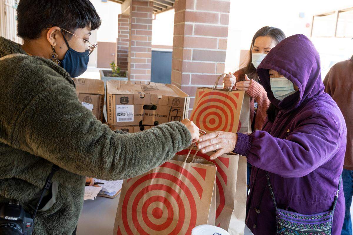 Moung Saeteurn, right, and her daughter, Mey Cresci, receive food from Asia Saechao, left, senior program coordinator at the Stockton Boulevard Partnership in South Sacramento on Saturday, Nov. 20.