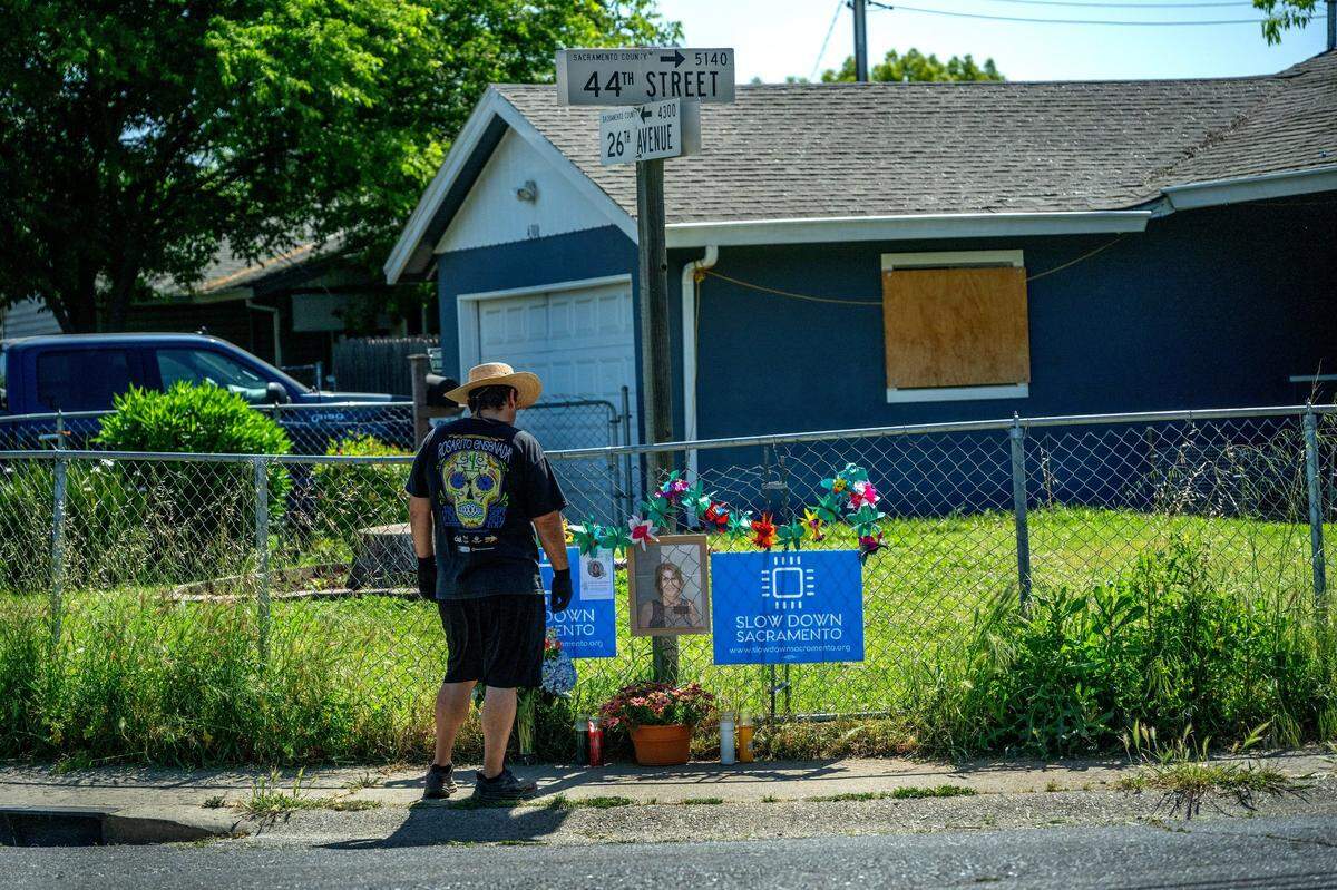 A neighbor looks at a memorial for Machelle Wilson at the corner of 44th Street and 26th Avenue in Sacramento on Monday. Wilson was walking her dogs when she was hit by a car while crossing the street in October. “I’ll keep the family in my prayers,” said the neighbor.