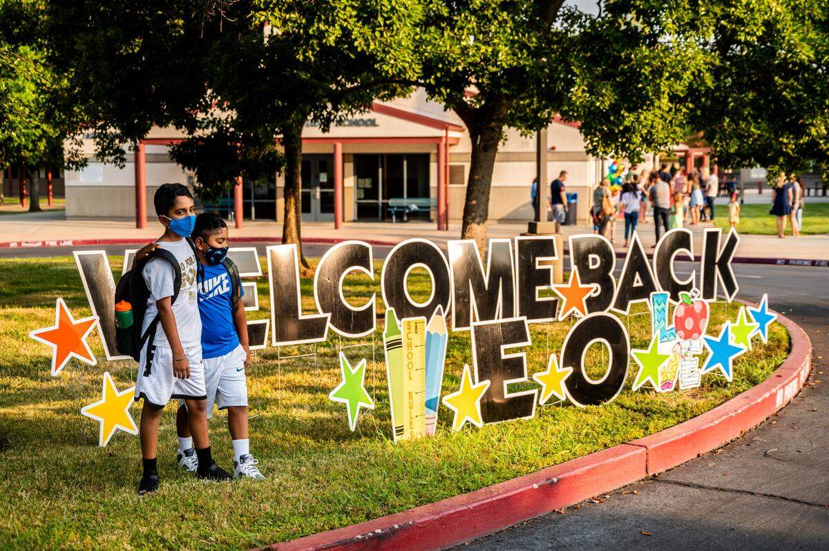 Students pose for photos at a welcome back sign on the first day of school at Empire Oaks Elementary School in Folsom on Wednesday, Aug. 11, 2021. After a year of distance learning due to COVID-19 related closures, students started full day in-person instruction five days a week in the Folsom Cordova School Unified School District.