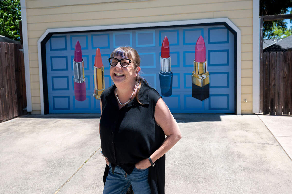 D. Oldham Neath, owner of Archival Gallery who coordinated the murals, stands in front of a residential garage door Wednesday, June 15, 2022, painted by artist Carrie Cottini. Her piece “Call Me Maybe” features five different tubes of lipstick, which is the artist’s signature subject. Sacramento’s Mural Alley is a beautification project that elevates businesses and residential spaces in the alley off of Folsom Boulevard between 32nd and 33rd streets in East Sacramento