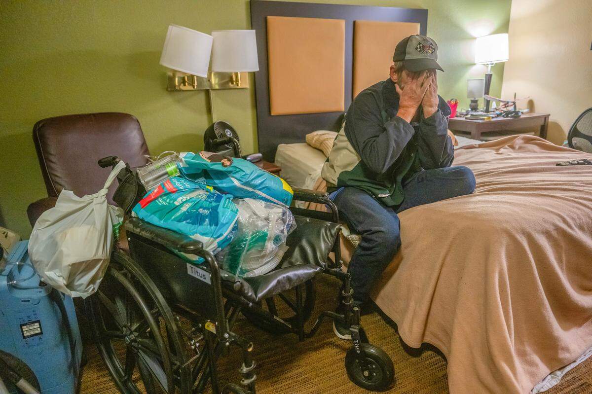 Steve Goble, 64, grieves on Dec. 6 at Extended Stay America hotel in Sacramento, as he sits next to the wheelchair and other medical apparatus that his partner Shonn Adams depended on before she died in the hospital days before.