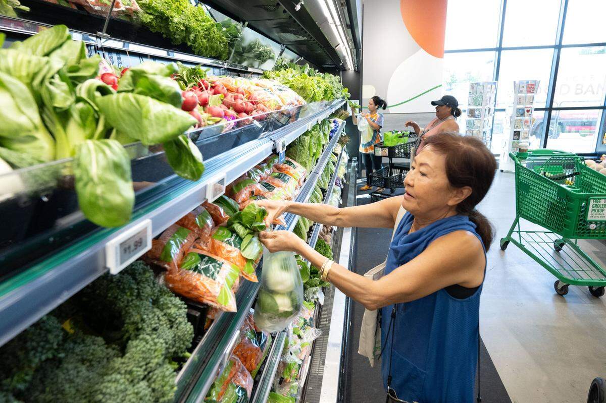 Scrichit Malakai of Rocklin picks bok choy during the grand opening of the first Amazon Fresh in Roseville on Thursday, Aug. 22, 2024.
