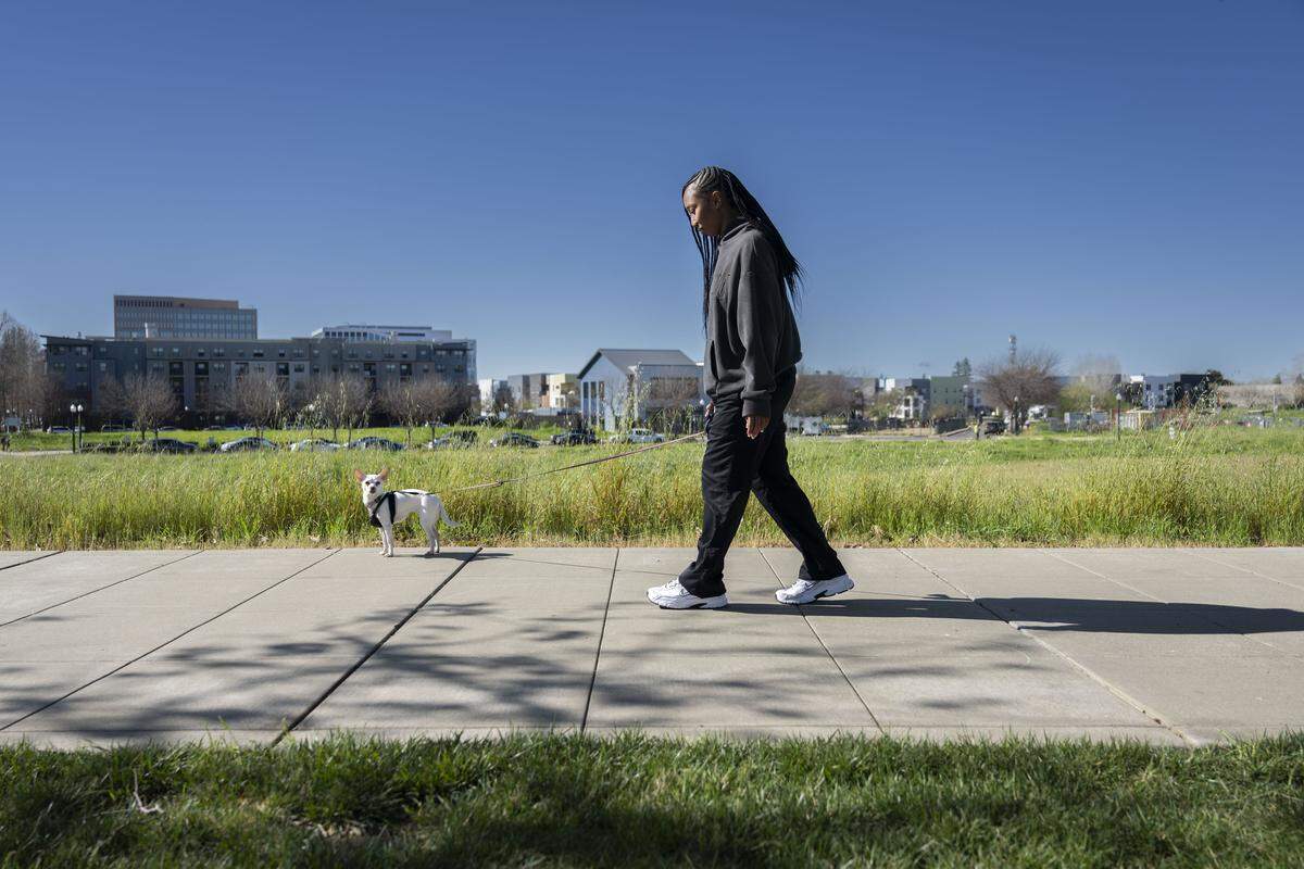 Shana McDaniels, a River District tenant, walks her dog Winter on Wednesday, March 4, 2026.