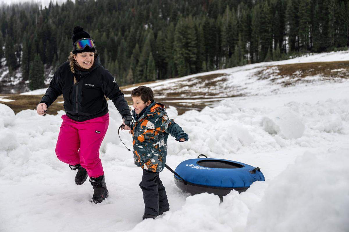 Fernanda Elias of Guadalajara, Mexico, and her five-year-old nephew finish a snow tube run at Palisades Tahoe on Thursday, Dec. 21, 2023. Many Tahoe-area ski resorts have limited runs open due to a lack of snow and warmer temperatures.