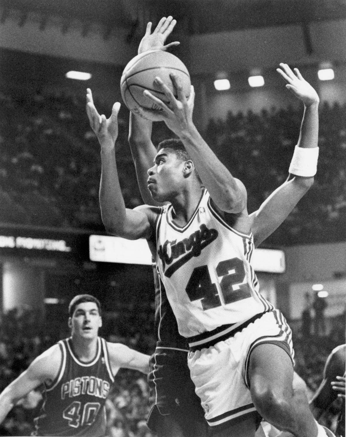 The Sacramento Kings' Pervis Ellison (42) drives past Isiah Thomas and Bill Laimbeer (40) of the Detroit Pistons for a layup during his rookie season of 1989-90.