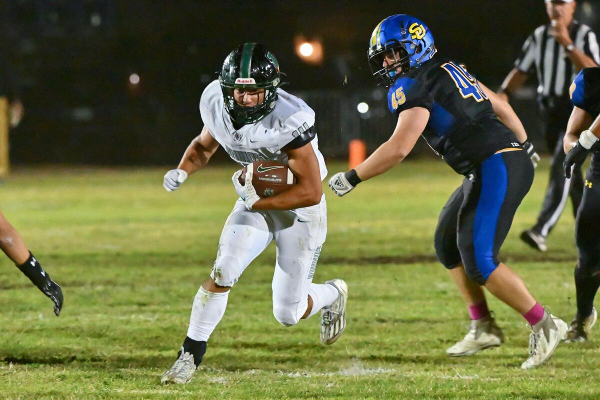 Twelve Bridges Raging Rhinos running back Nathan Crawford (14) runs the ball past the Sutter Huskies’ Eric St. Onge (45) for a first down on Thursday.