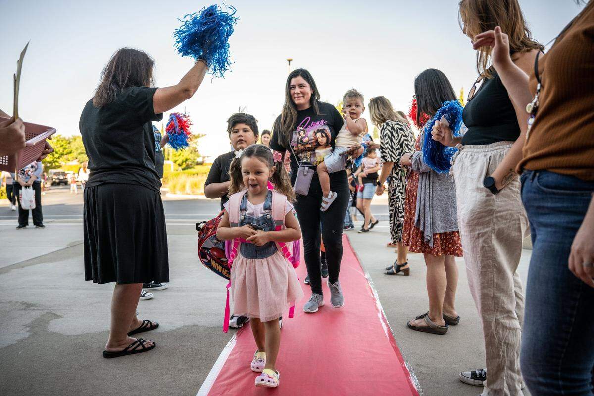 Velina Siewell, 4, a student at Navigator Elementary School in Rancho Cordova, leads her brothers Michael Barajas, 6, and Jaxon Siewell, 1, and mother Trina Barajas as they arrive Tuesday, Aug. 8, 2023, for the first day of school in the Folsom Cordova Unified School District. Students were greeted by teachers and staff along the red carpet.