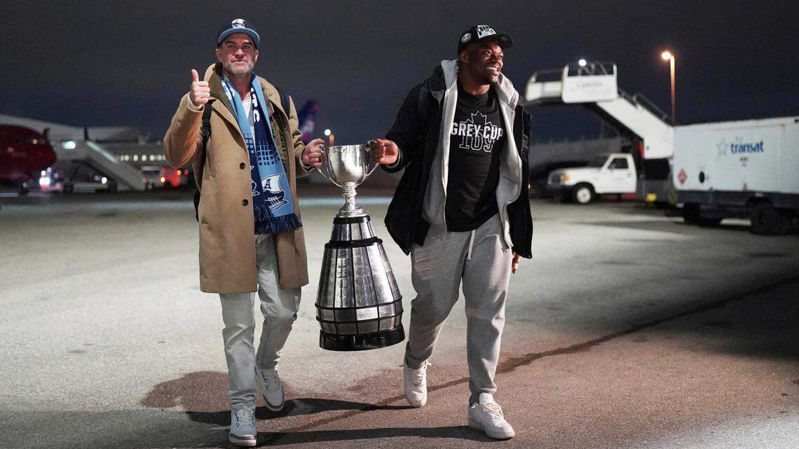 Coach Ryan Dinwiddie and linebacker Henoc Muamba of the Toronto Argonauts hold the Grey Cup as they arrive at Toronto Pearson International Airport in Mississauga, Ontario, on Nov. 21. The Argonauts defeated the Winnipeg Blue Bombers on Sunday to win the cup.